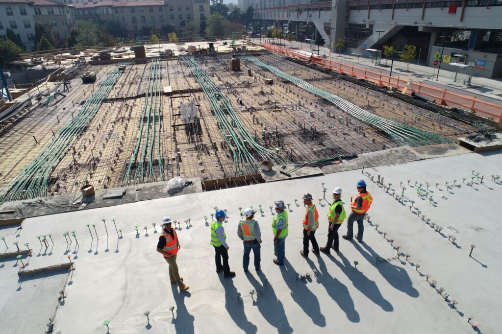 Construction workers overlook a steel building’s foundation