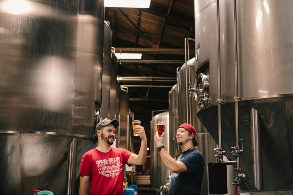 Two men near beer tanks in a brewery.