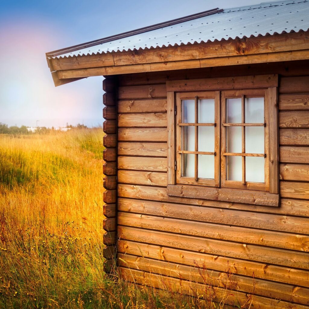 Roof pitch: Wooden cabin with metal roof in sunny grassland.