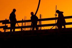 A construction crew working on a building at sunset.