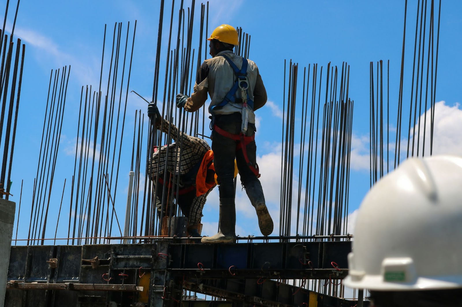 Construction workers stand on top of a metal structure.