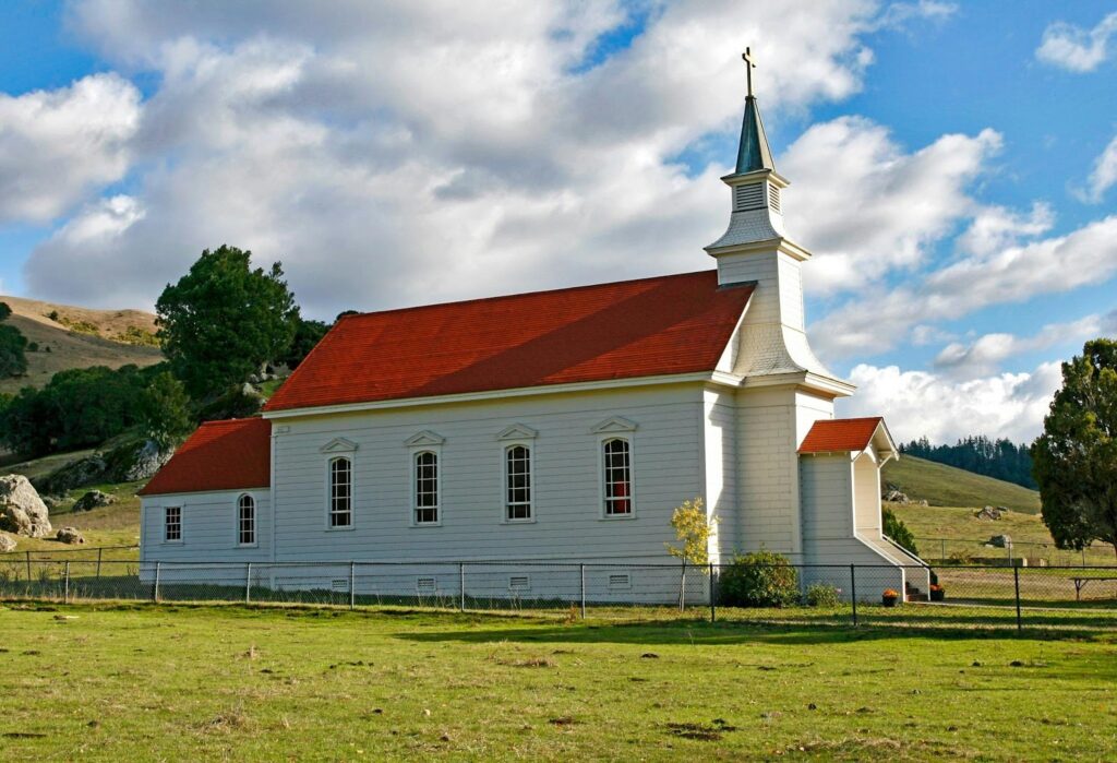 A church in the countryside with rolling hills.