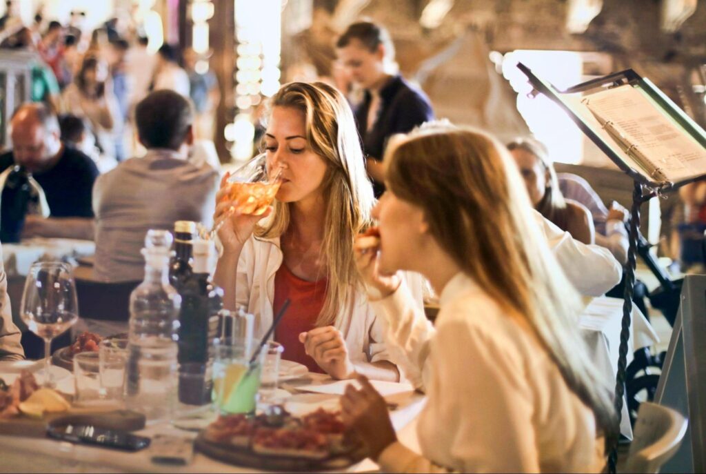 Several people eating and drinking at a restaurant.