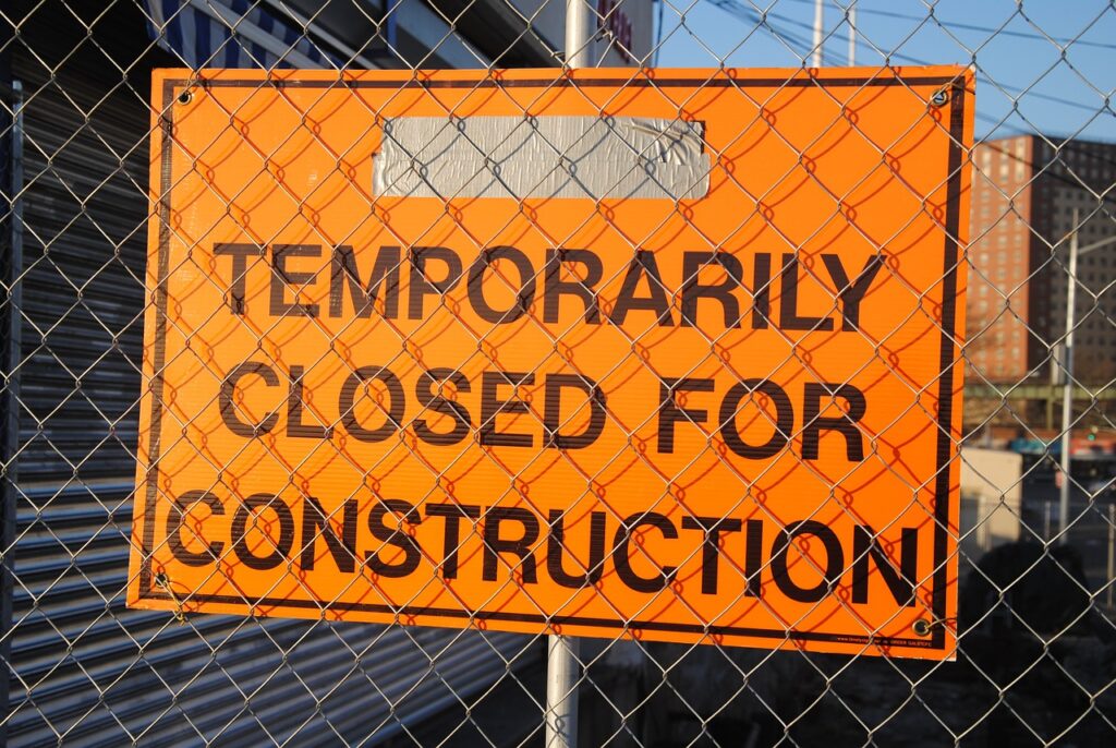 A chain-link fence with an orange sign saying, “Temporarily closed for construction.”